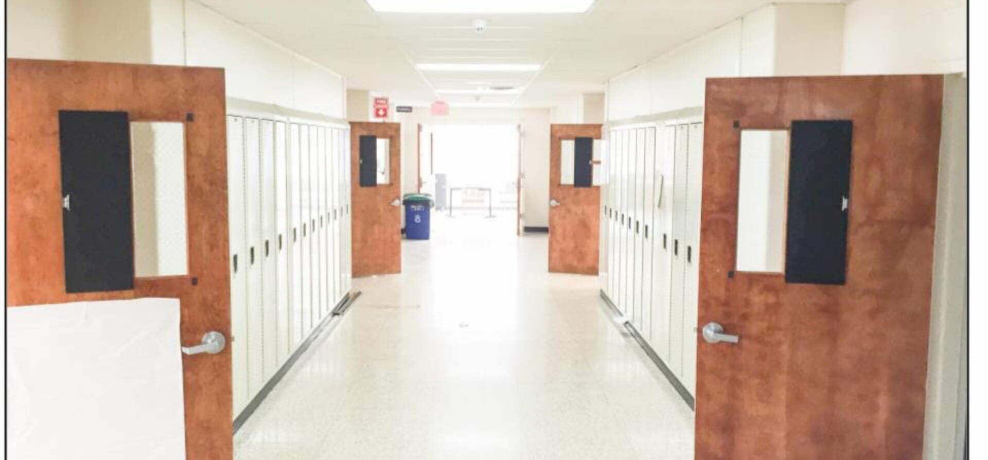 A hallway with lockers and a door open.